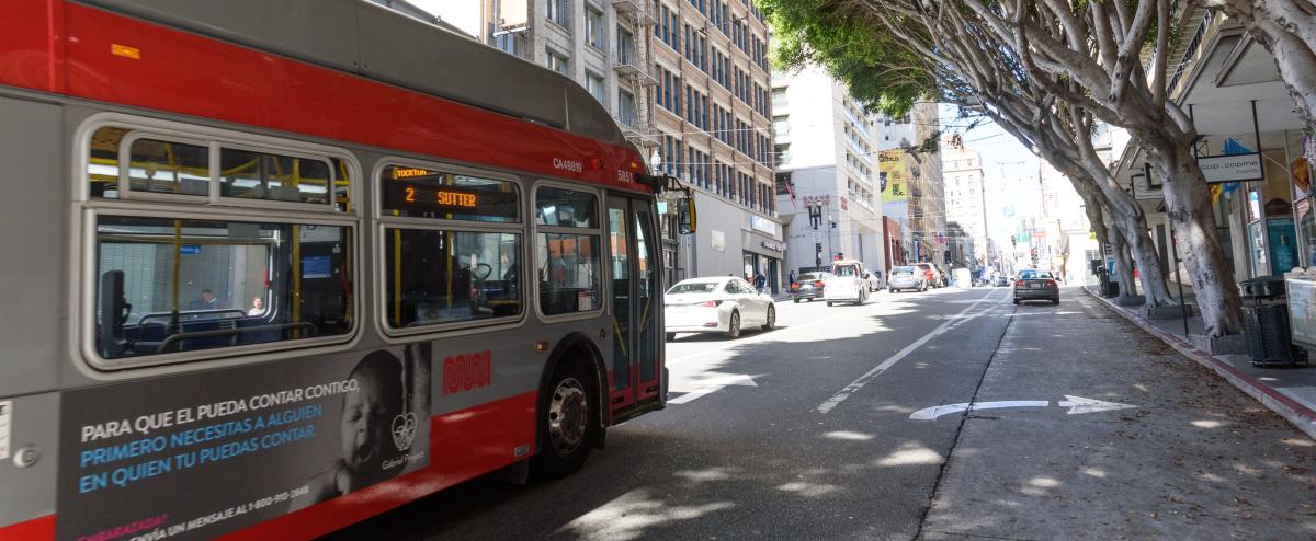 A 2 Sutter coach driving past trees downtown San Francisco.
