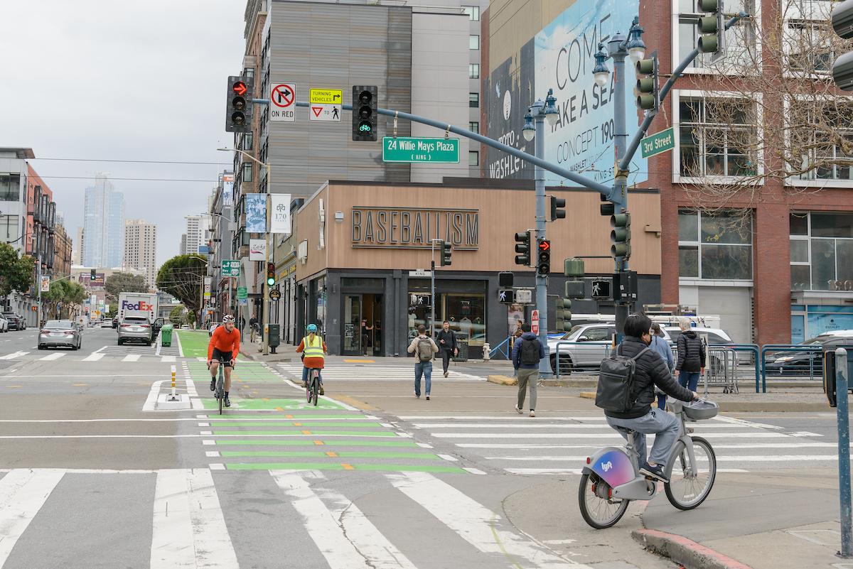People use a two-way bikeway as others cross an intersection. People use a two-way bikeway as others cross an intersection.