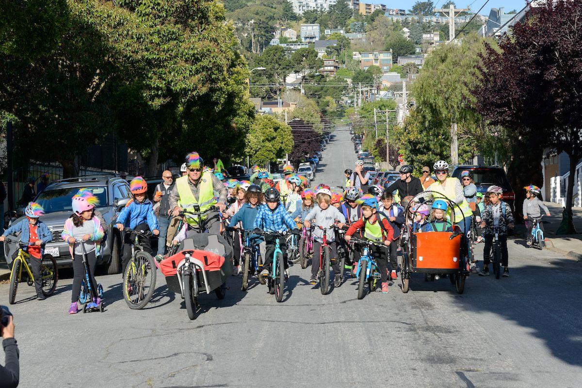 Many young people and adults ride bicycles down a residential street. Many young people and adults ride bicycles down a residential street.