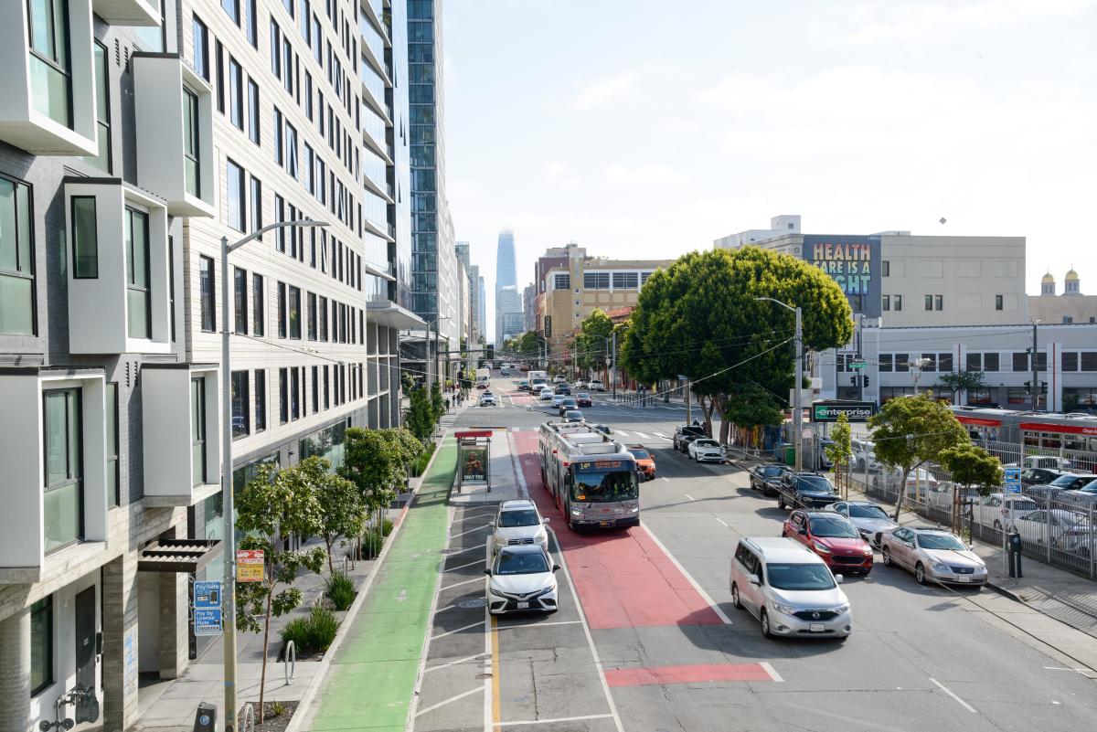 14 mission bus in a red transit lane drives down a street near other vehicles.
