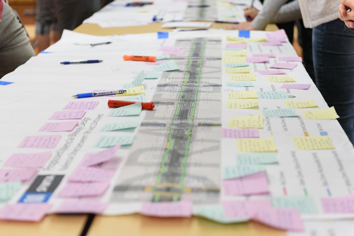 A close-up image of sticky notes with suggestions on a long print-out of the proposed side-running lanes from a Valencia open house. There are several dozen sticky notes visible, as well as pens, markers and highlighters..