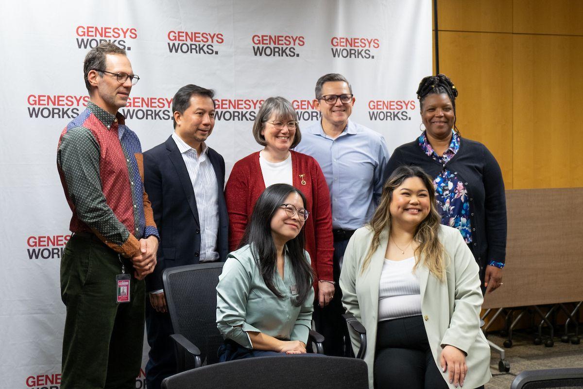 SFMTA managers who have supervised Genesys Works interns smile for a group photo in a conference room.