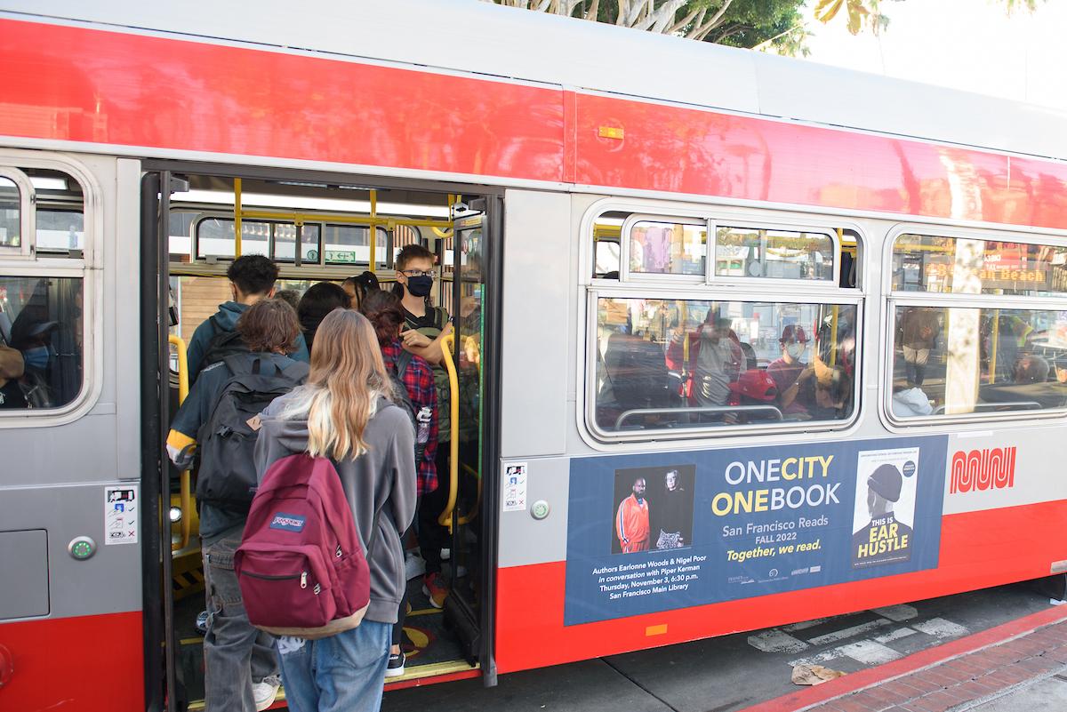 People wearing back packs board a bus.
