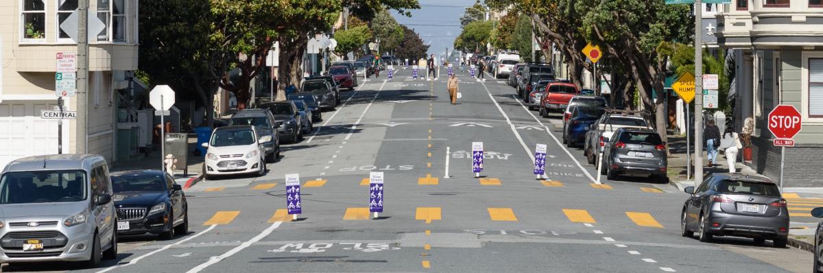 Photo of Golden Gate Avenue from a distance with Slow Streets delineators and people walking in the street