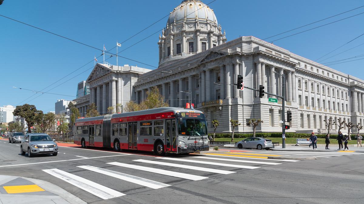 A 49 Van Ness-Mission bus heads down a dedicated transit lane past San Francisco City Hall.