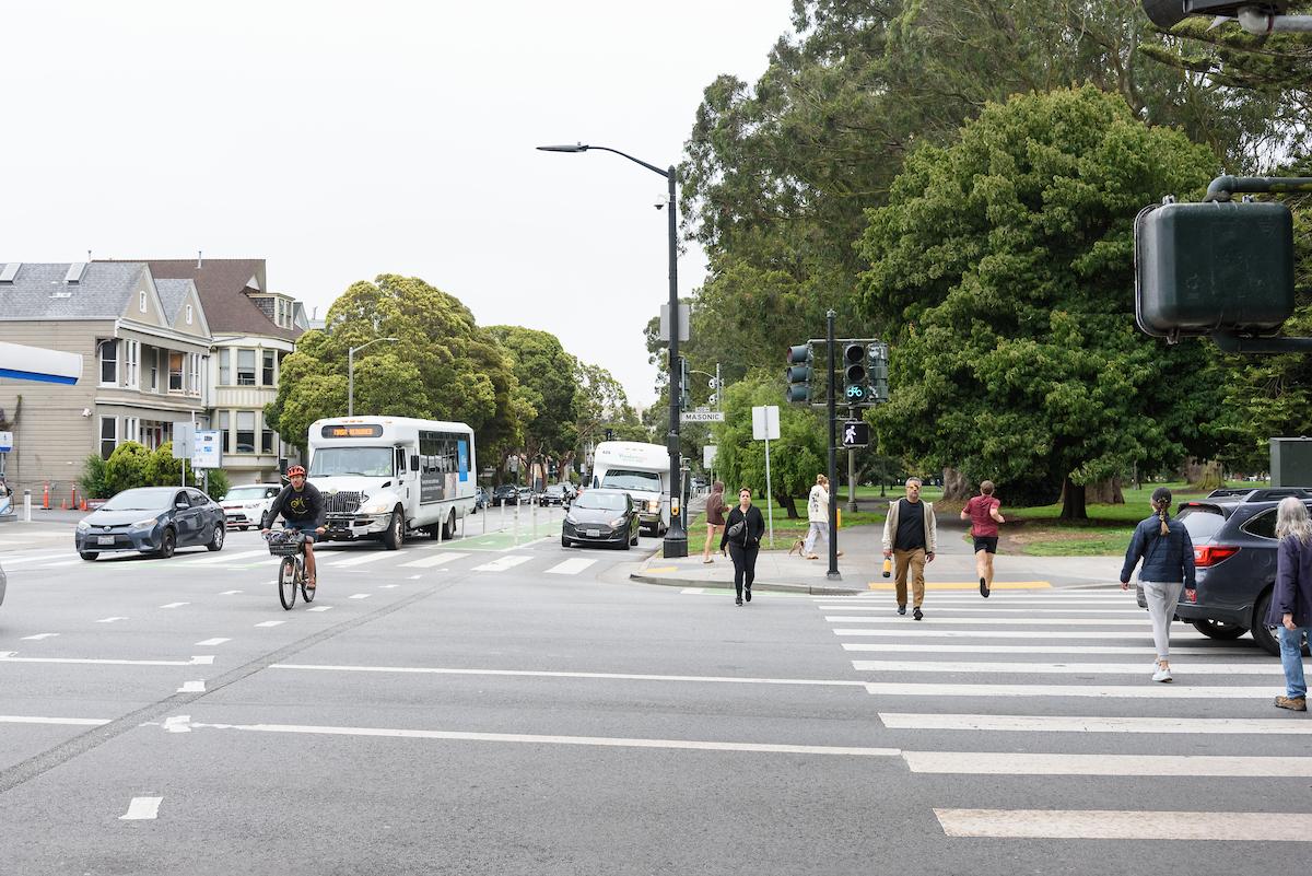 People bike and walk across an intersection of the Panhandle.
