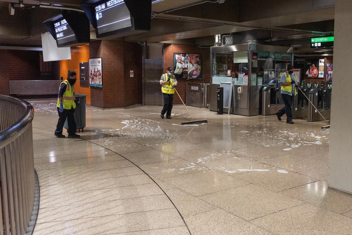 Custodians mop the floor of a Muni station.