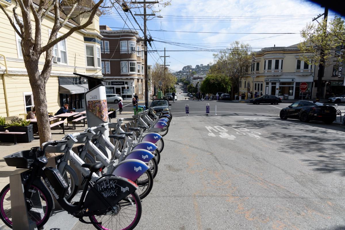 Several Bikeshare bikes lined up at a bikeshare rack near a Slow Street. 