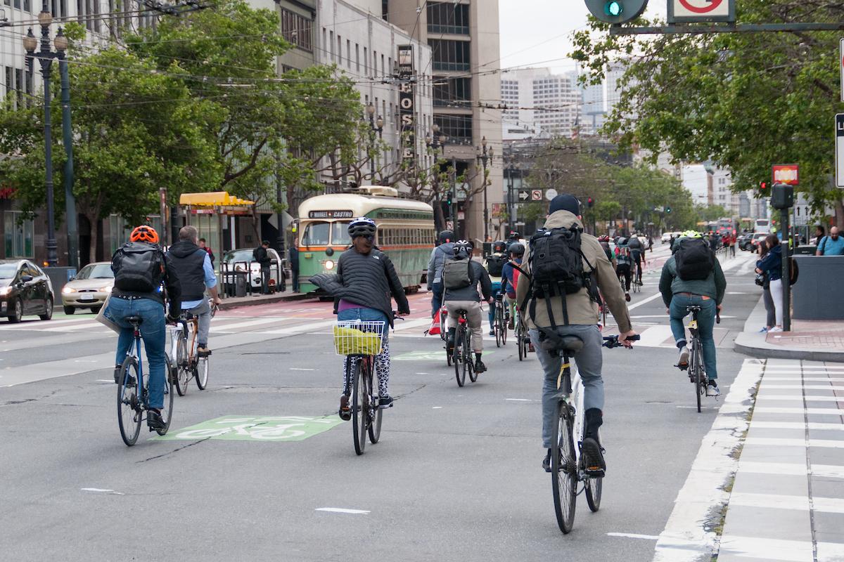 Several people bike on Market Street near F Market historic streetcars.