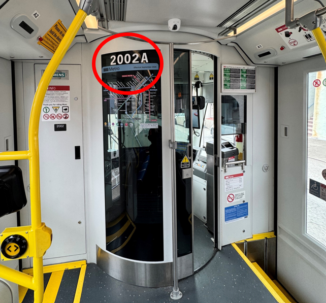 Where to find vehicle numbers inside a Muni Metro train Inside a Muni Metro train facing the operator's cabin
