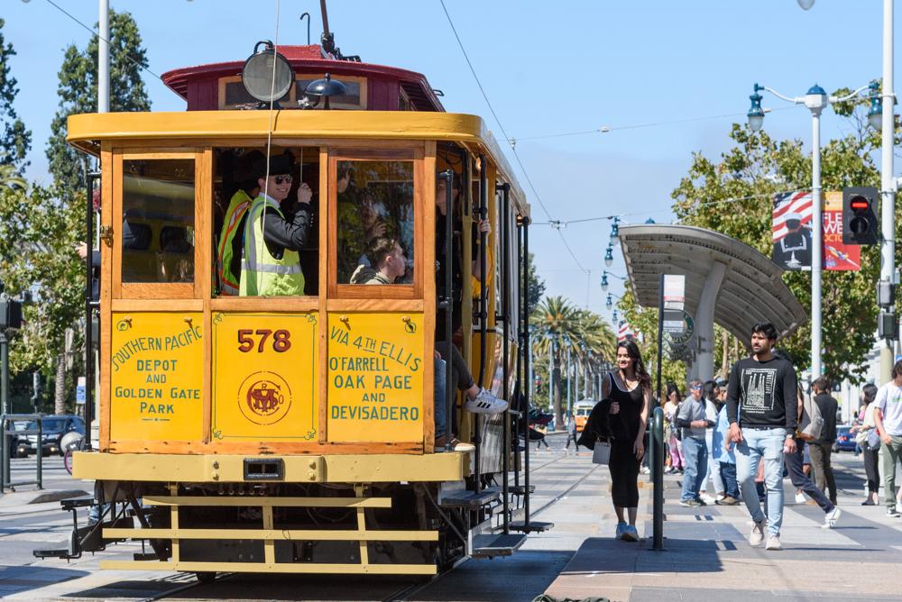 People board a yellow and tan historic streetcar during the 2024 Muni Heritage Weekend.