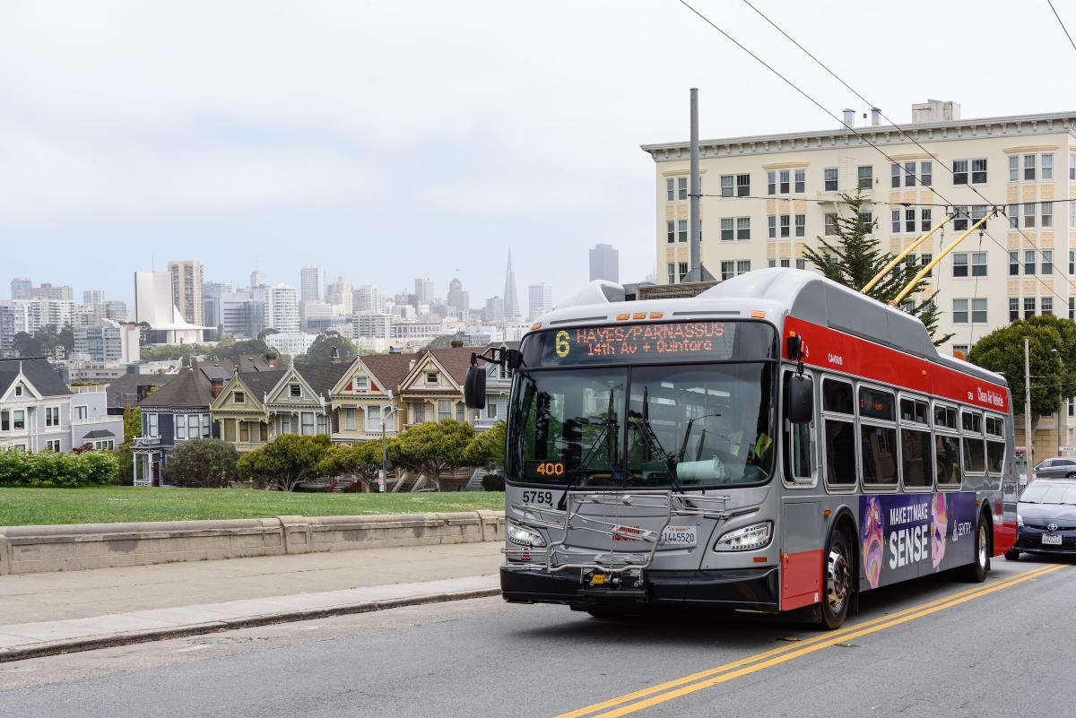 New 6 Hayes-Parnassus bus heads up a hill passing Alamo Square and the Painted Ladies houses.