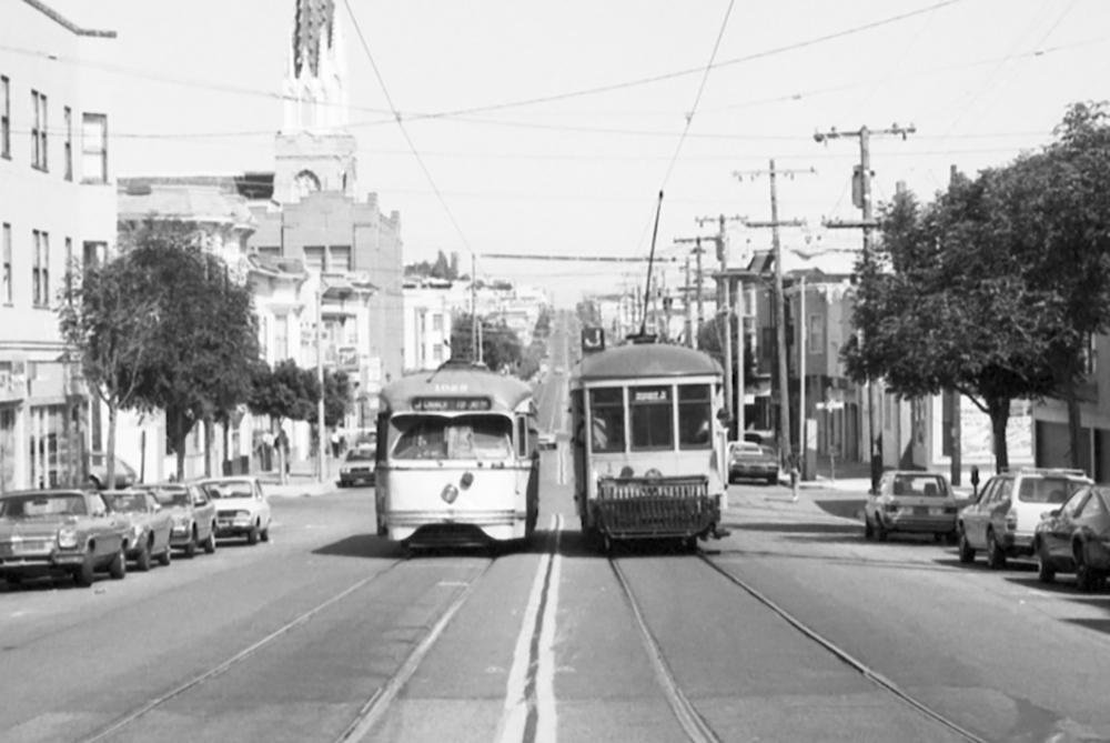 Two historic Muni streetcars pass each other on Church Street. Black and white photo from 1982.