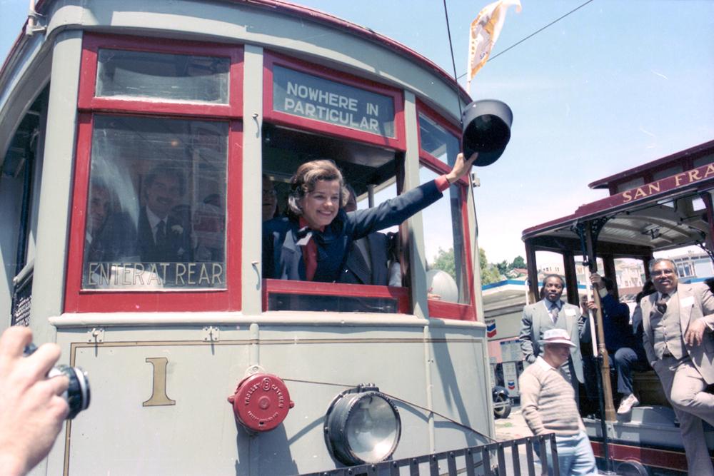 Former San Francisco Mayor Dianne Feinstein waves a Motorman's hat out the front window of Muni Car 1.