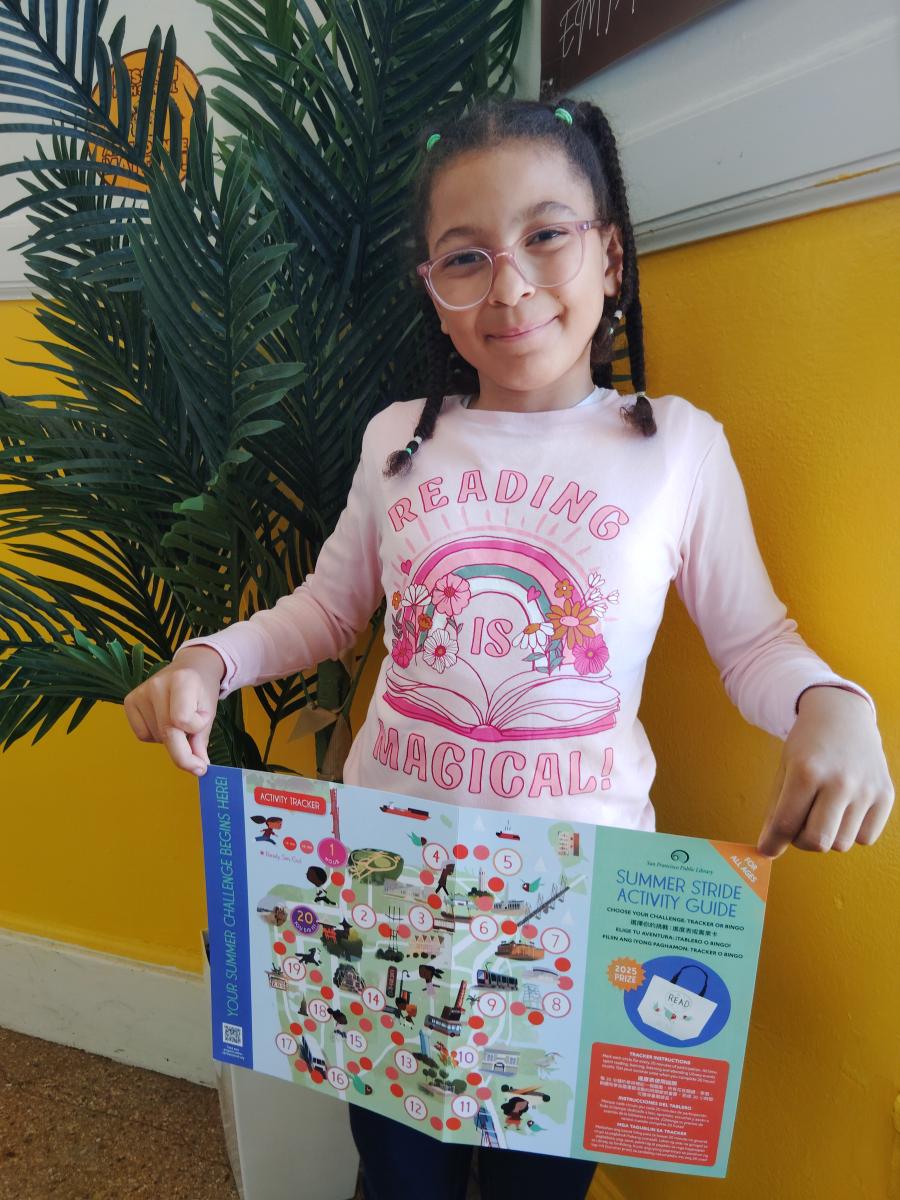 Photo of a girl standing near a plant and holding a Summer Stride printout activity tracker.