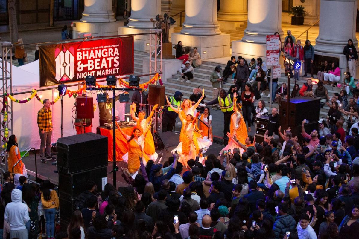 Crowd of people dancing on stage and in the street for the Bhangra and Beats Night Market.