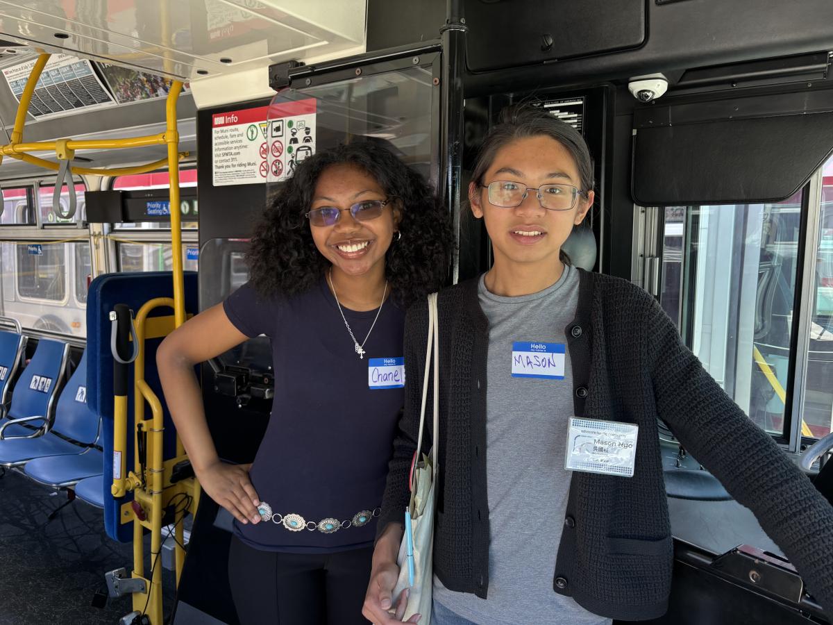 Two people standing inside a bus.