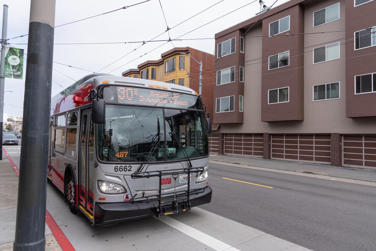 A bus on a street in front of a building.