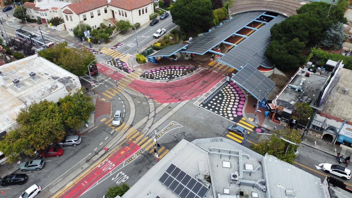 An overhead photo of West Portal Station shows new street murals, a bikeshare station and planters outside the station.