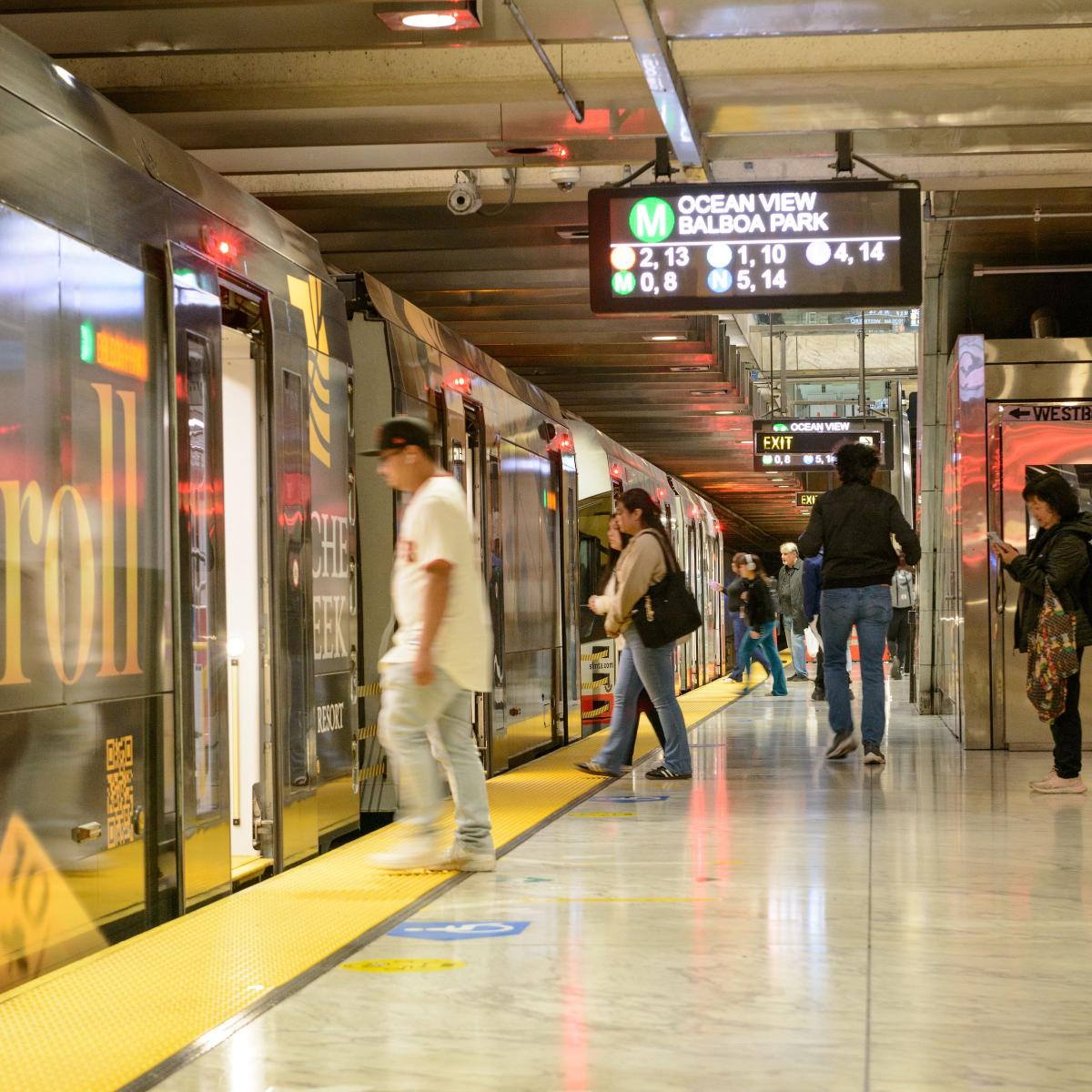 People entering a train at a Muni Metro platform.