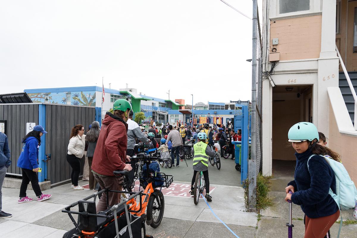 People on bikes and scooters in front of a building.