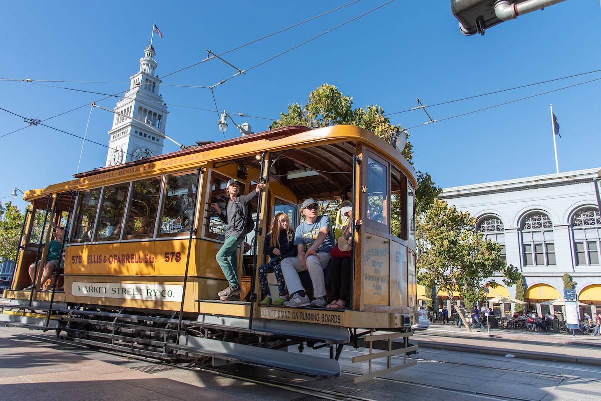 People riding a vintage vehicle during Muni Heritage Weekend.
