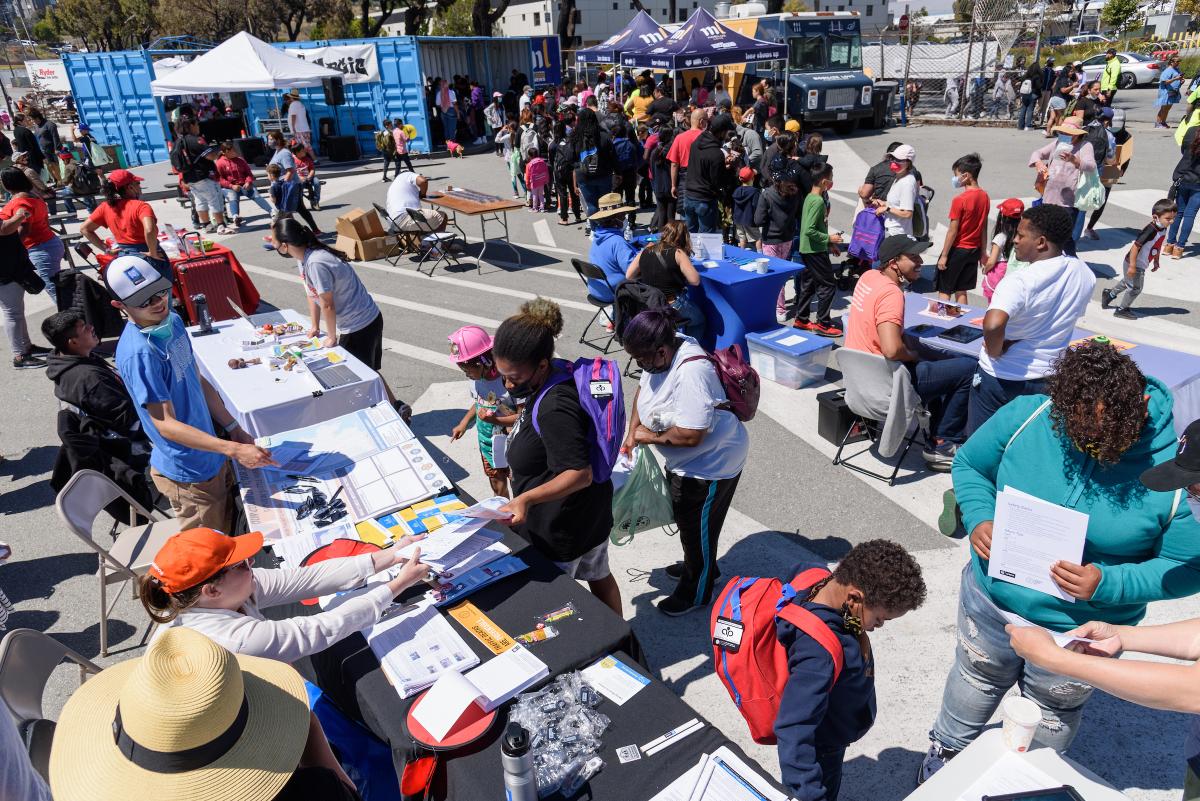 Aerial view of people stopping by a tabling event where Muni staff share information.