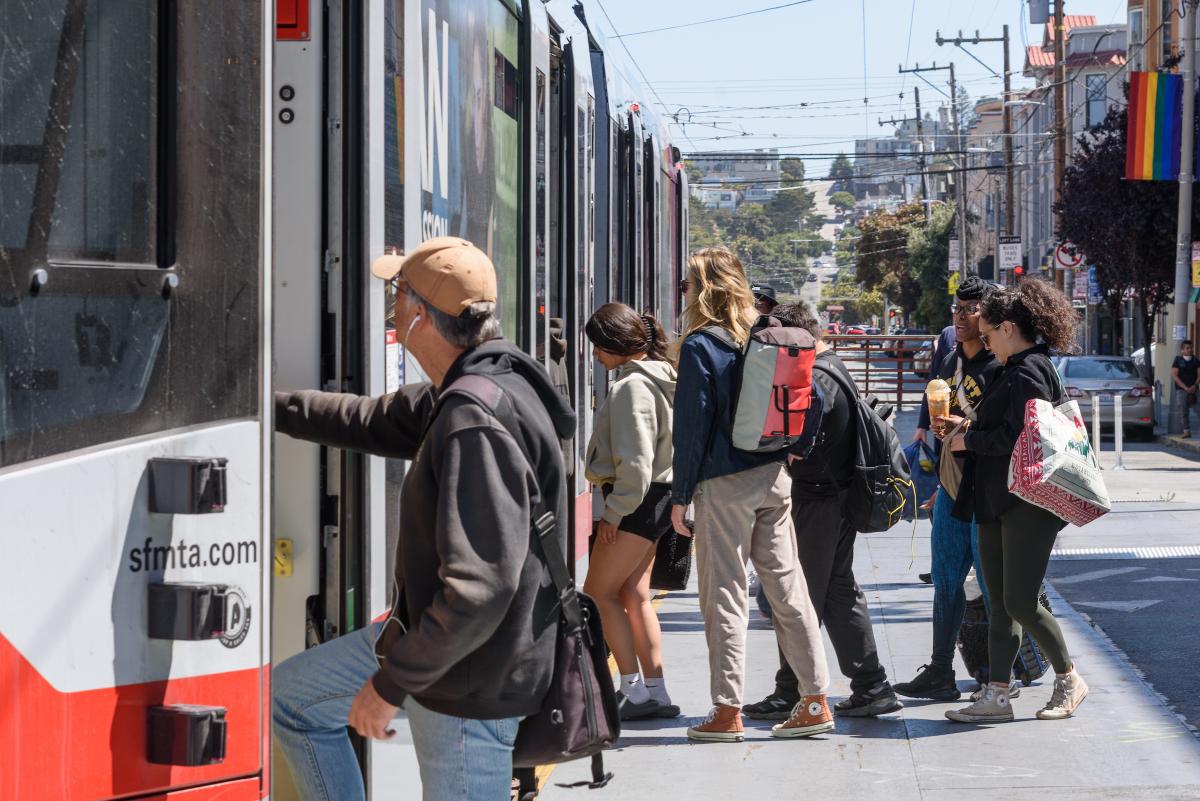 Several people board a J Church train near Church and Market streets.