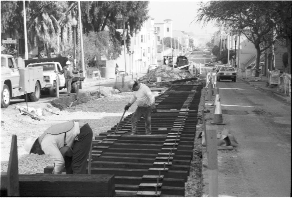 Black and white photo of construction workers laying tracks to build part of the F Market route in the early 1990s.