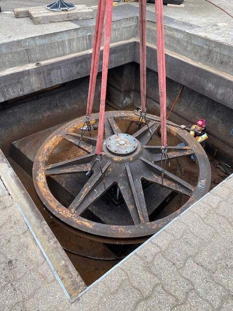 Closeup of a large sheave underground as a crew member stands nearby.