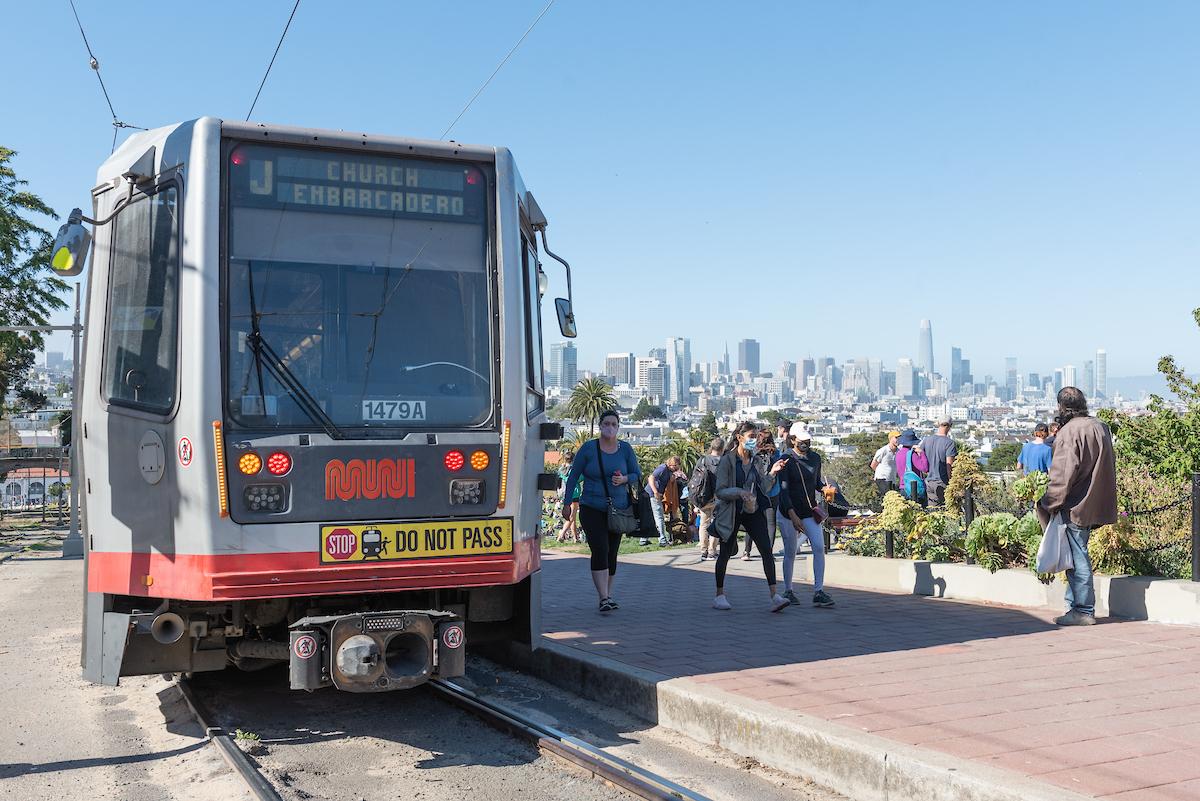 Our Breda light rail vehicles have carried San Franciscans through decades of change and connection. People near a train and light rail tracks with the skyline in the background
