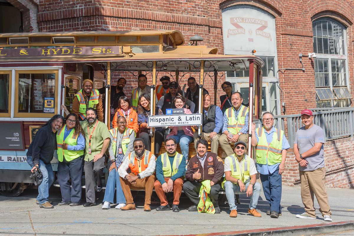 People sitting on a cable car in front of a building.