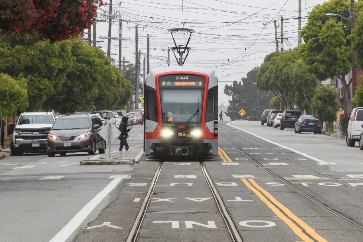Muni rider boards an M train in a dedicated transit lane on San Jose Avenue.