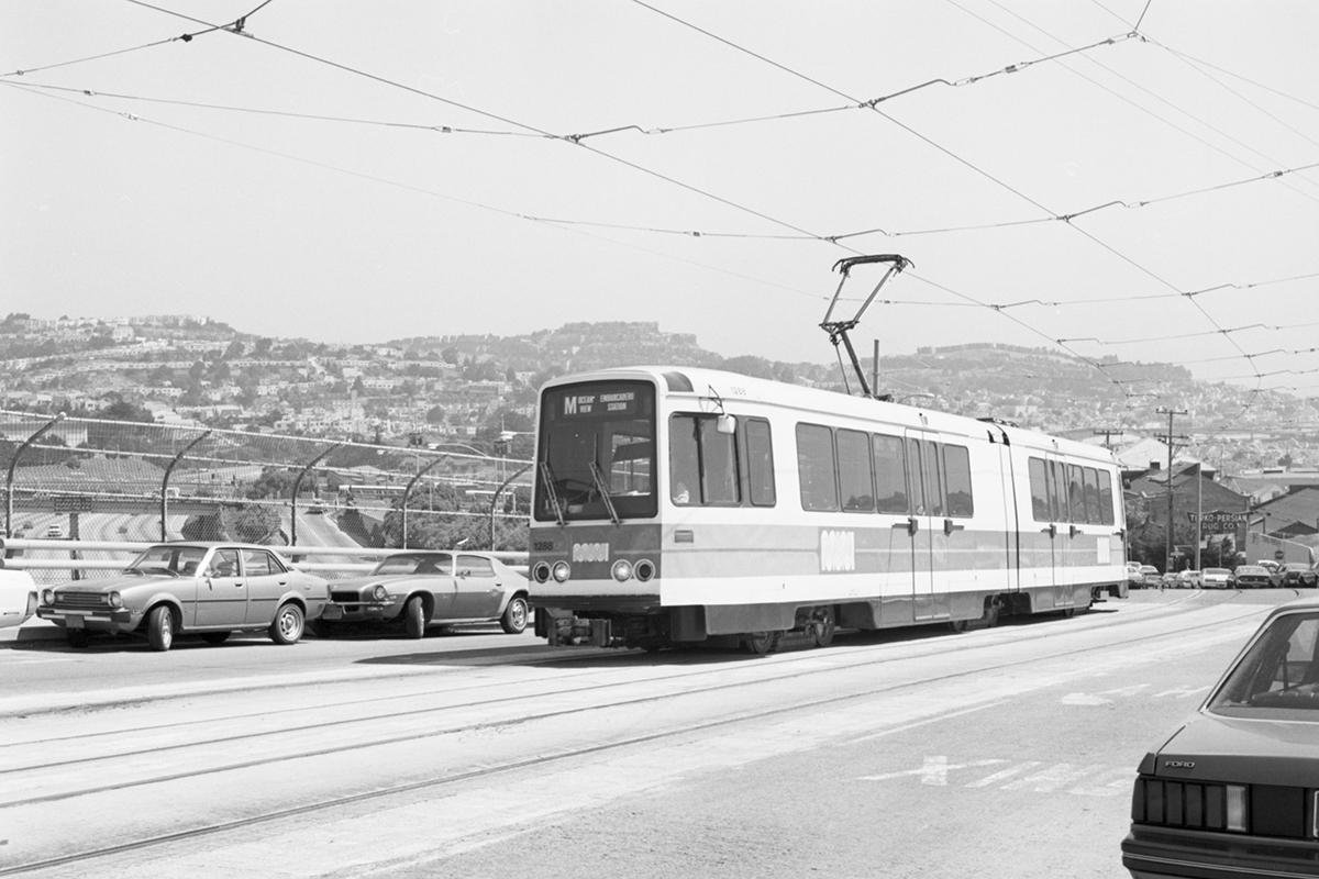Black and white from 1980 showing an LRV vehicle running on new tracks along the M line by I-280.