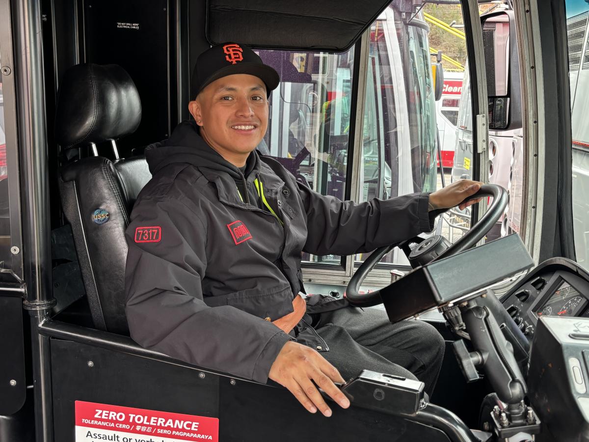 A person sitting in the driver’s seat of a bus. 