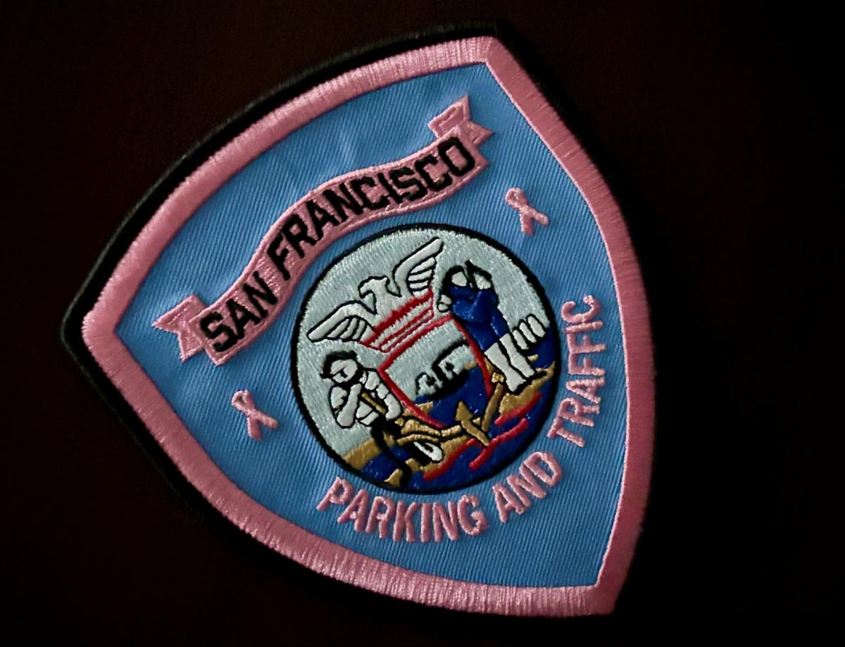 A blue and pink woven patch with letters and an image on it. Text on patch says: "San Francisco Parking and Traffic."