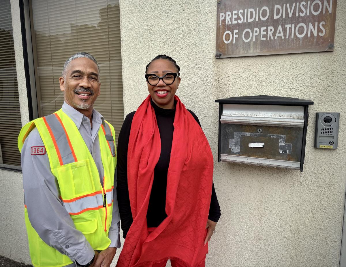 Two people standing in front of a plaque with writing on it.