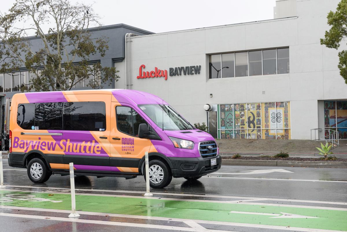 Bayview Shuttle van drives near a protected green bikeway. 