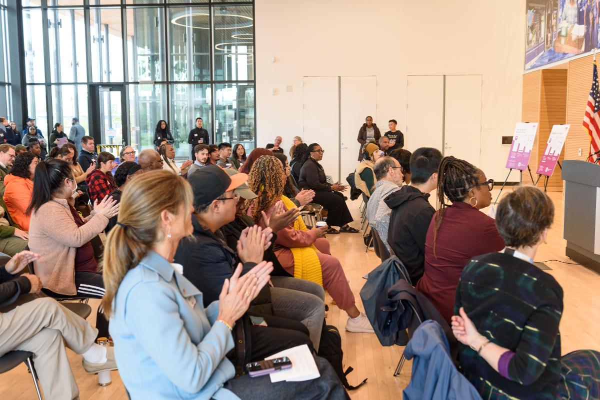 Group of people clapping during an event for the Bayview Shuttle.