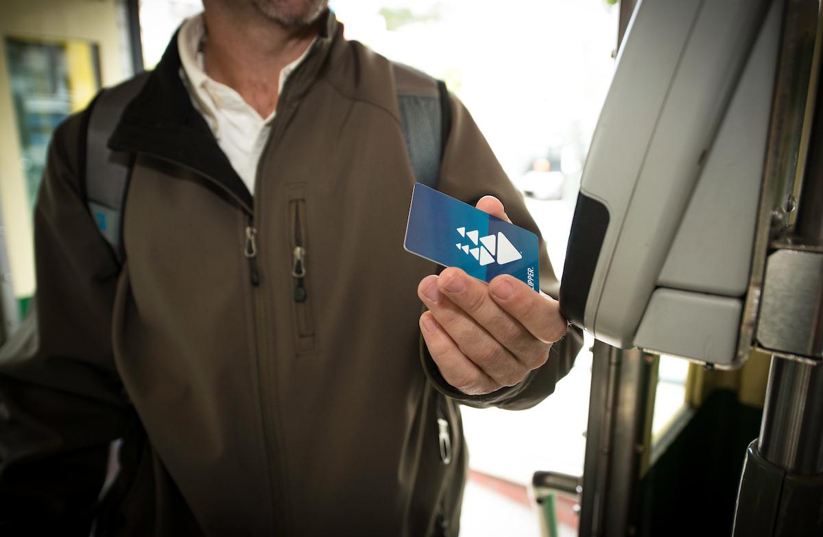A person holding a Clipper card near a machine.