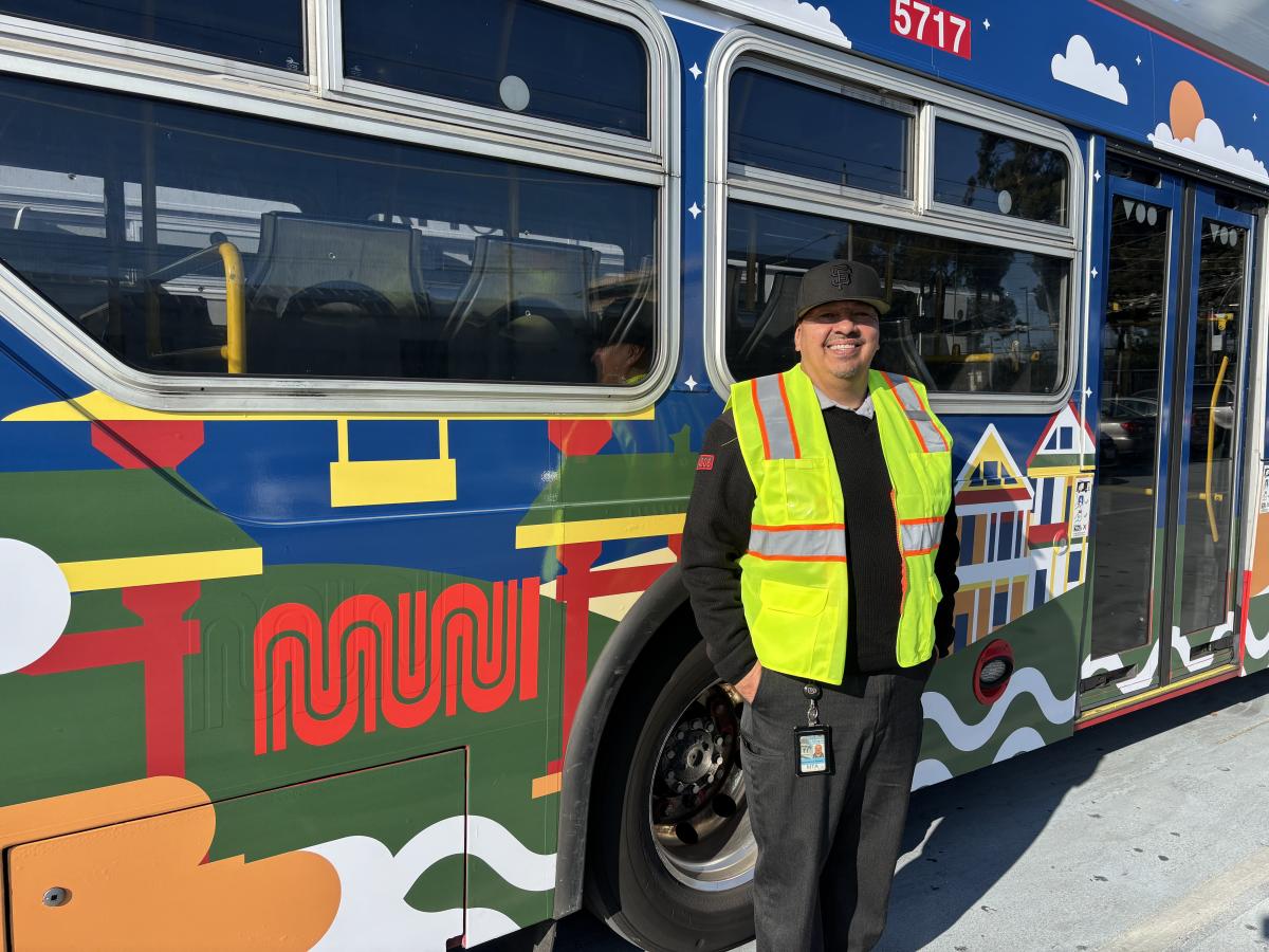 A person in front of a brightly colored bus.