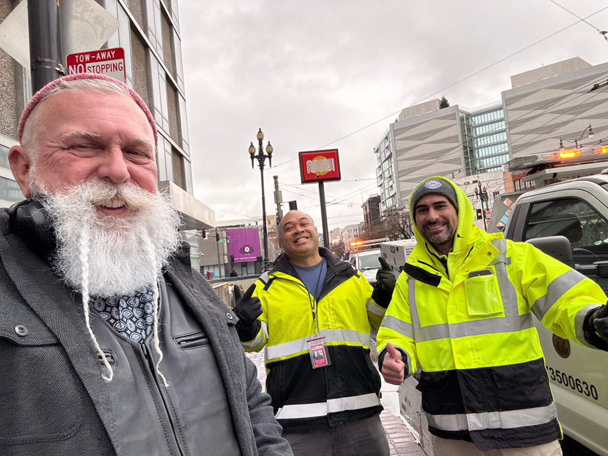 Three SFMTA staff take a fun selfie on a downtown street.