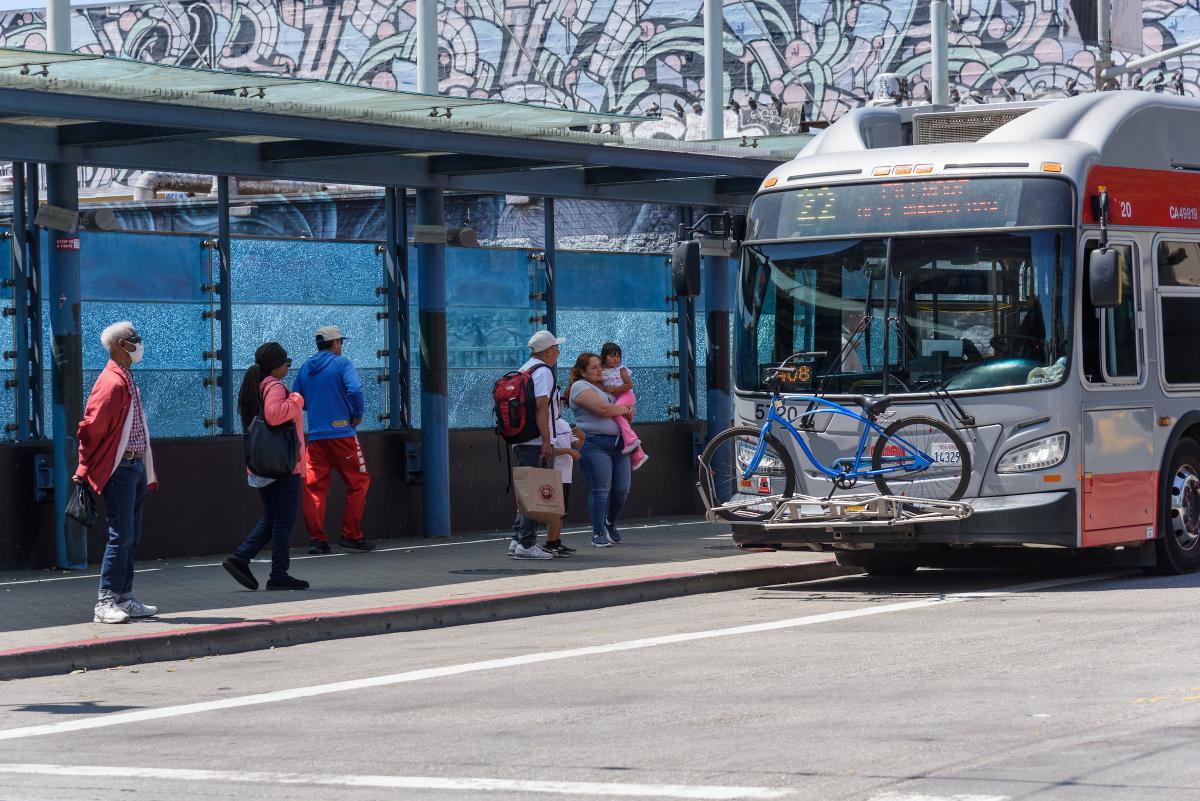 People walk toward a 22 Fillmore bus to board.