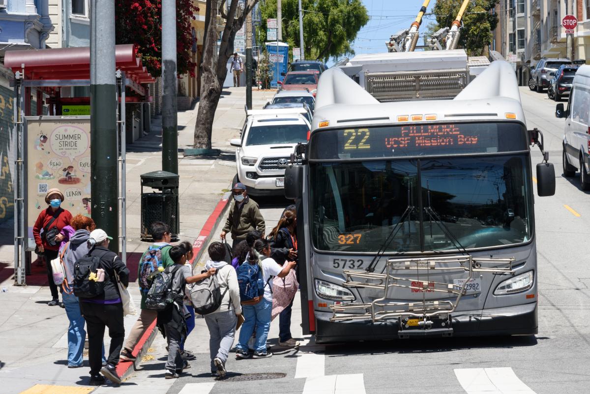 Students stand in line to board a 22 Fillmore.