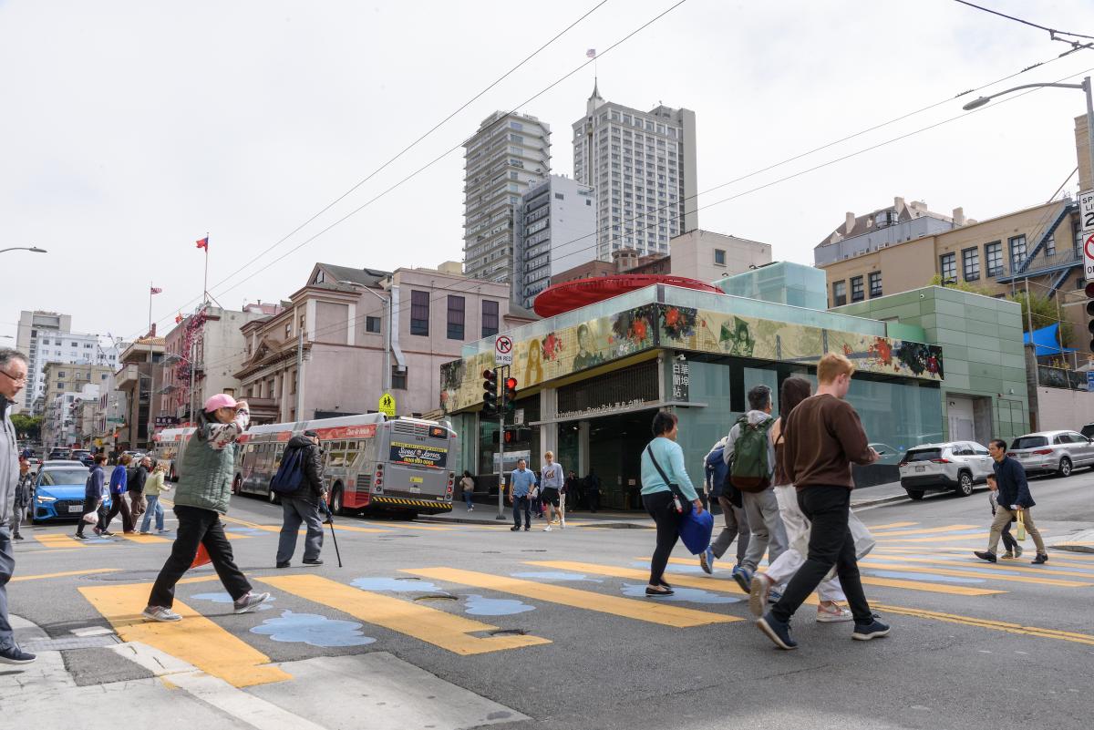 Several people cross a street near Chinatown - Rose Pak Station, which now has C-Band technology cell service underground.