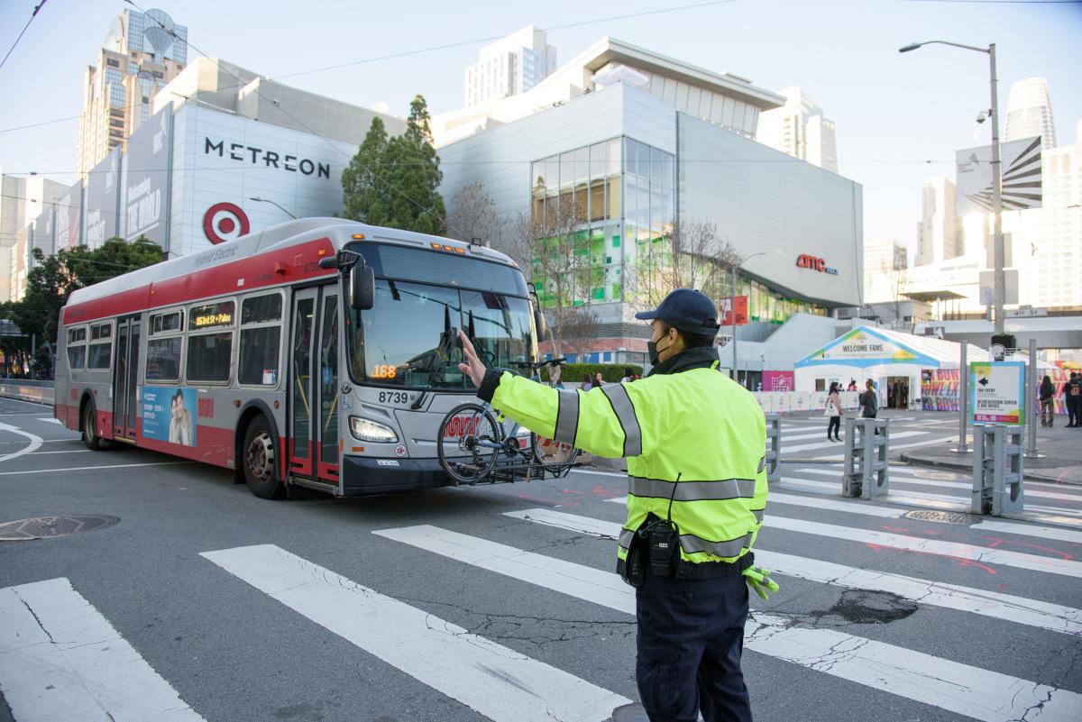 Parking control officer wearing a yellow safety vest directs traffic new Super Bowl LX events.