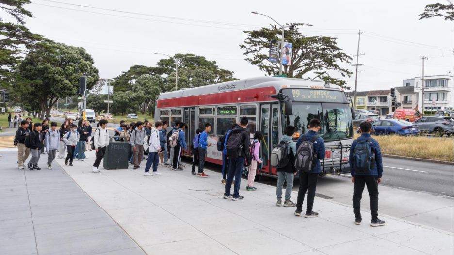 Dozens of young people wait to board a 29 Sunset. 