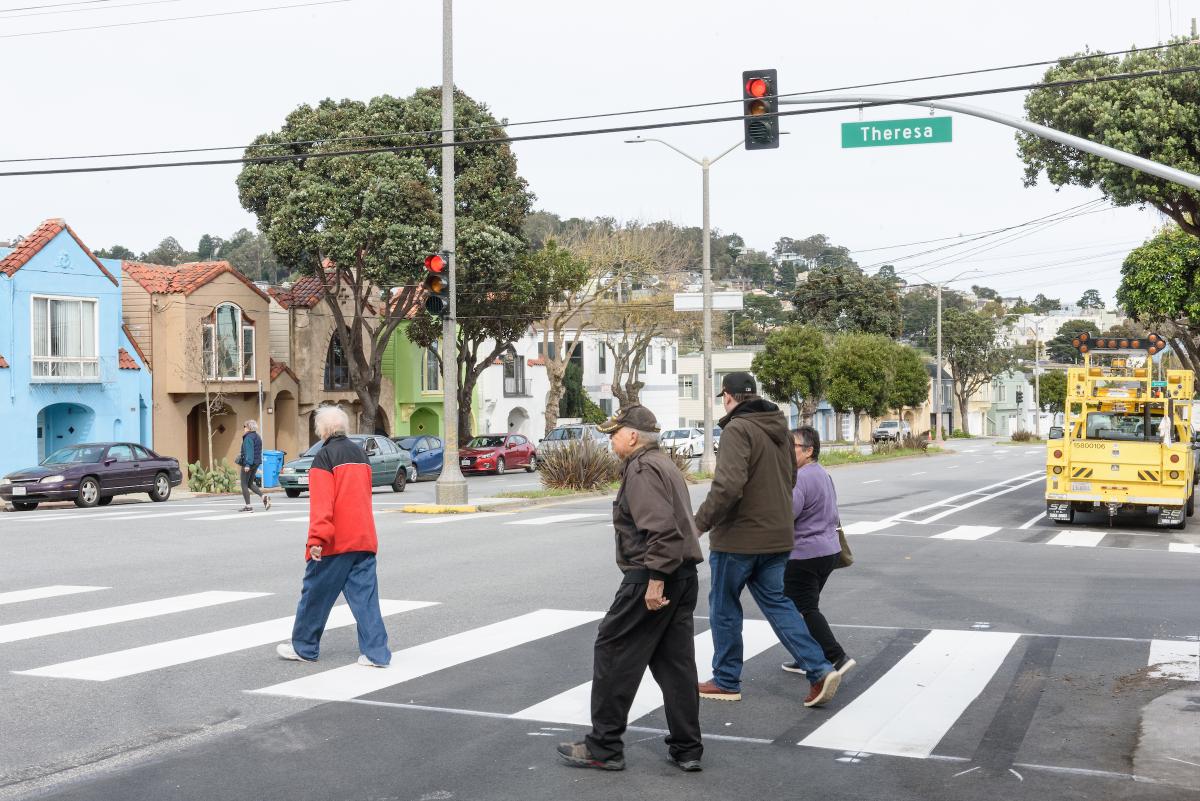 People cross a street at a stoplight. 