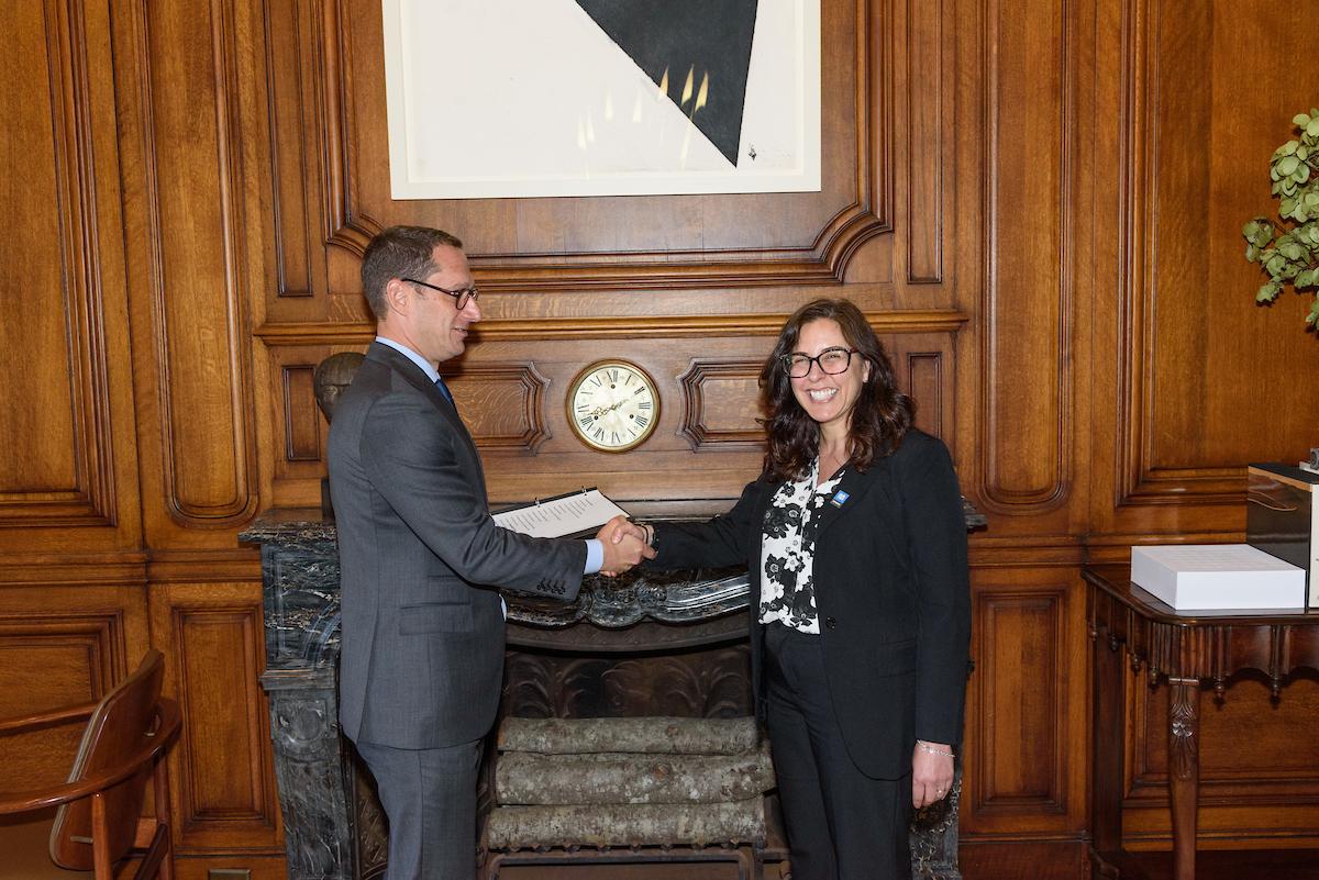 Director of Transportation Julie Kirschbaum shakes hands with Mayor Daniel Lurie in an office with wood paneling.