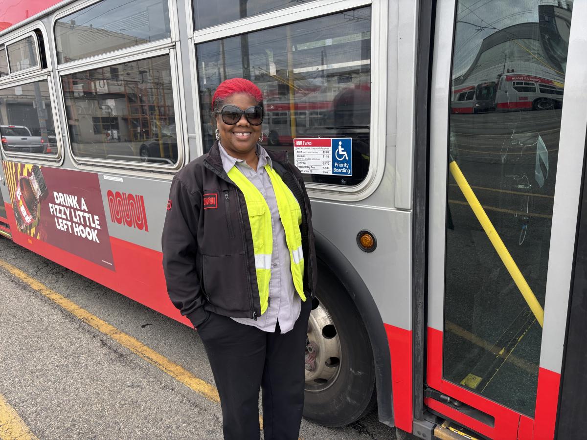 Operator Shanita Anderson stands next to a Muni bus.